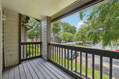 A balcony with a view of a street and trees.