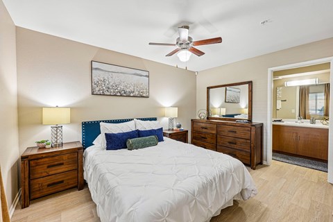 A bedroom with a large bed, a dresser, and a mirror.