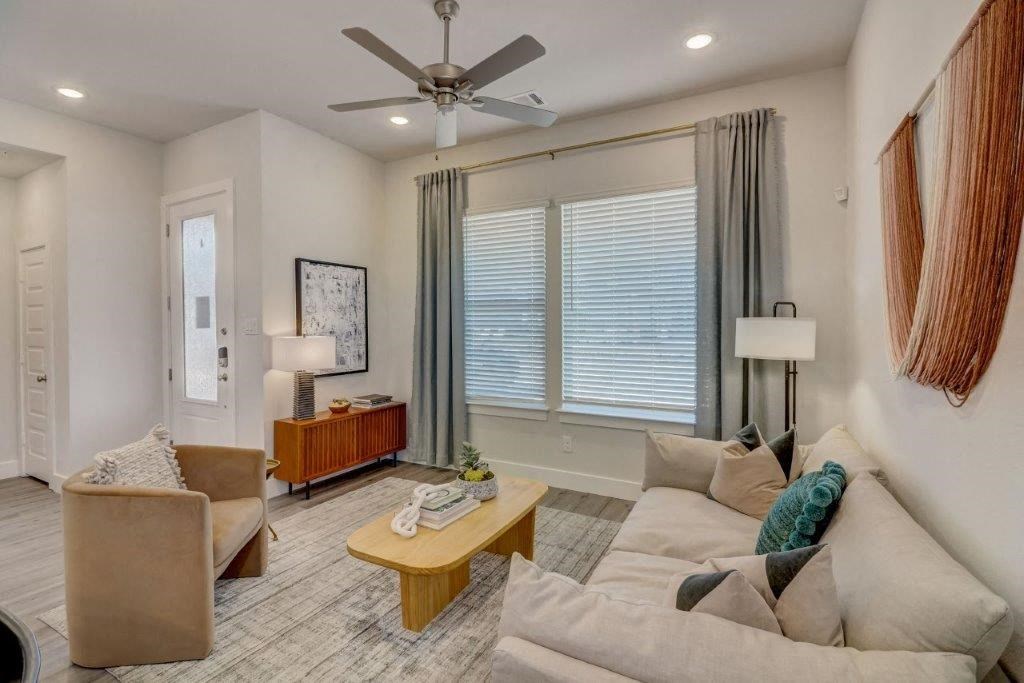 Single Family Homes in Hurst TX for Rent - Mission Town Square - Living Room with Hardwood Flooring, a Ceiling Fan, Large Windows, and a Door to the Outside