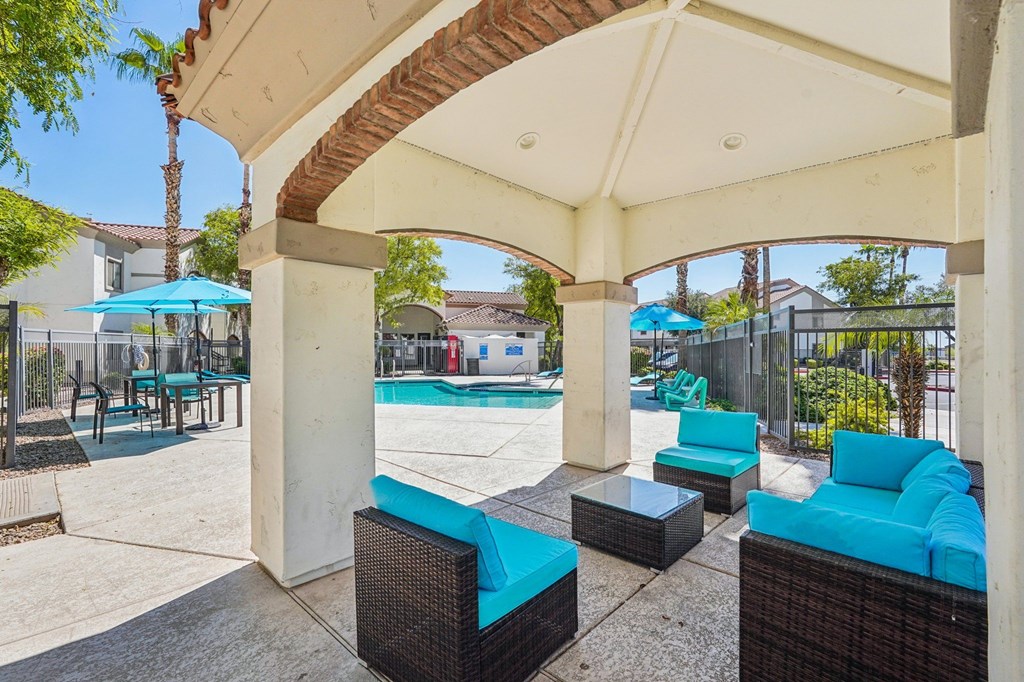 A patio with a pool and a blue umbrella.