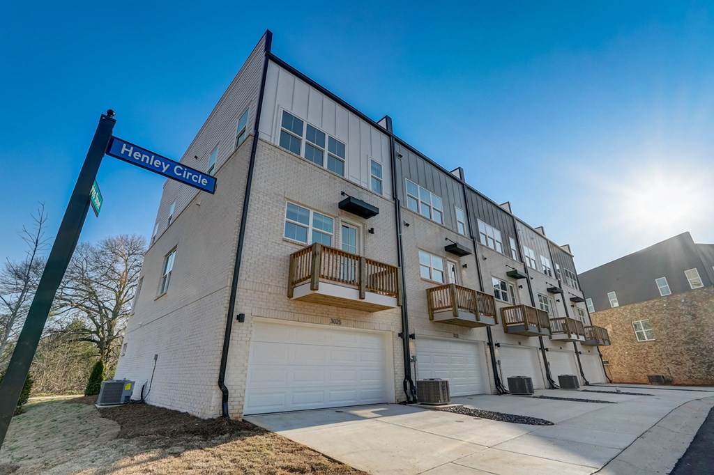 Back exterior of Henley Avondale townhomes in Avondale Estates, GA, featuring elegant patio and balcony retreats in a pet-friendly community.