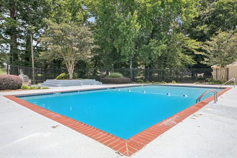 A rectangular pool with a red border and a metal fence around it.