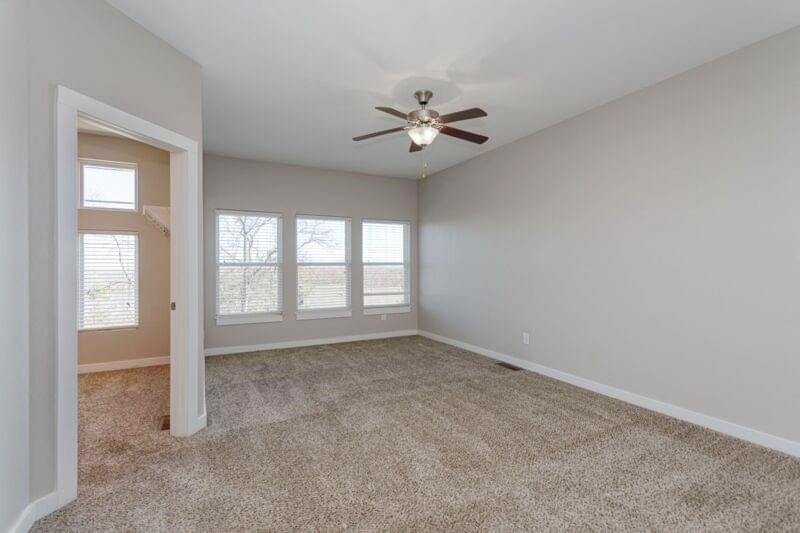 an empty living room with a ceiling fan