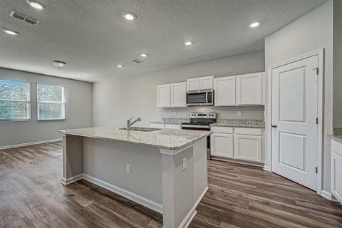 Modern kitchen with white cabinets, granite countertops, and a central island.