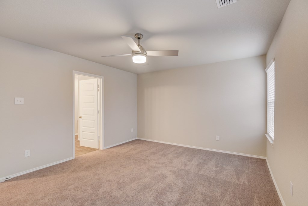 an empty living room with a ceiling fan and a door to a closet
