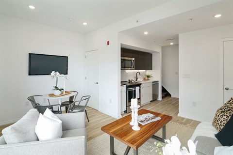 A modern living room with a grey couch, a wooden coffee table, and a flat screen TV mounted on the wall.