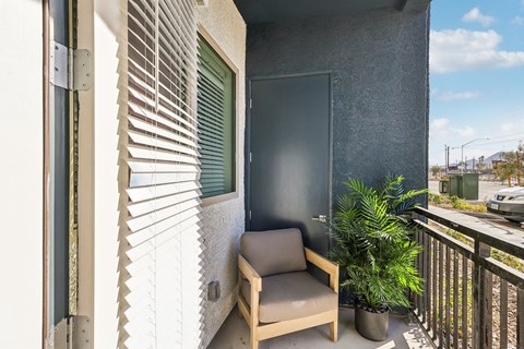 A balcony with a chair and a plant.