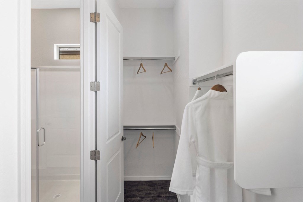 A white robe is hanging on a rack in a small room.