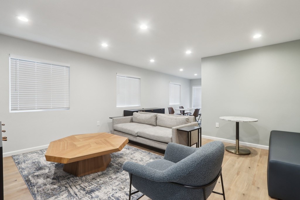 A modern living room with a grey sofa, a wooden coffee table, and a grey armchair.