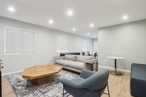 A modern living room with a grey sofa, a wooden coffee table, and a grey armchair.