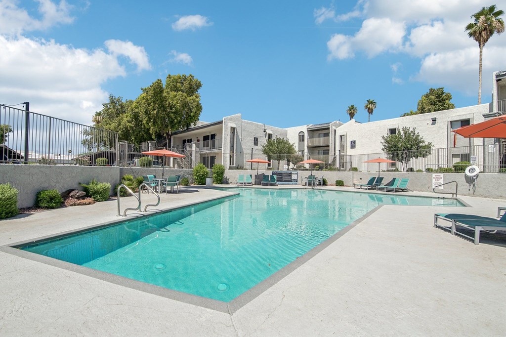 A large swimming pool in front of a building with a fence around it.