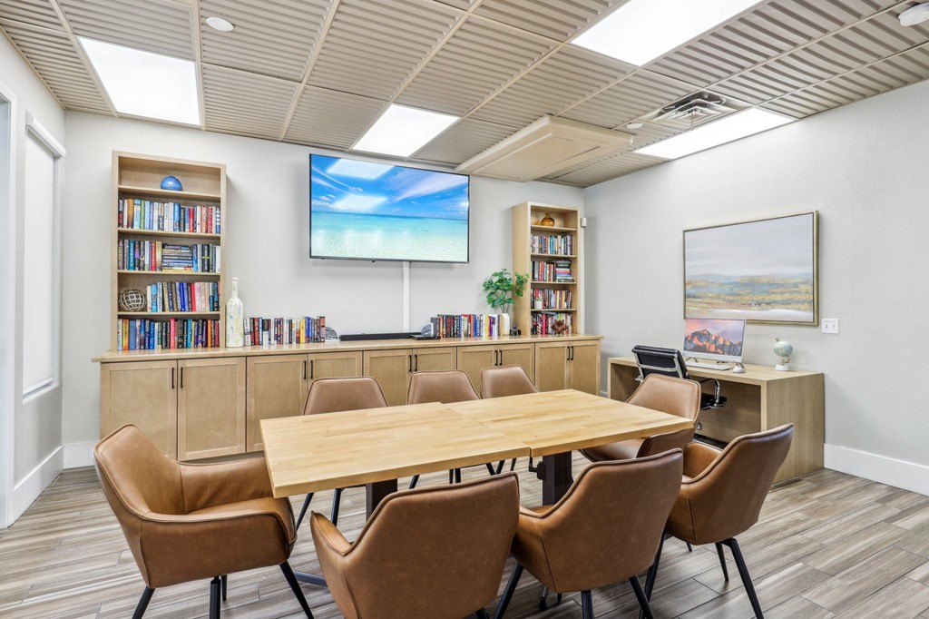 A conference room with a large table, chairs, and a screen displaying a beach scene.