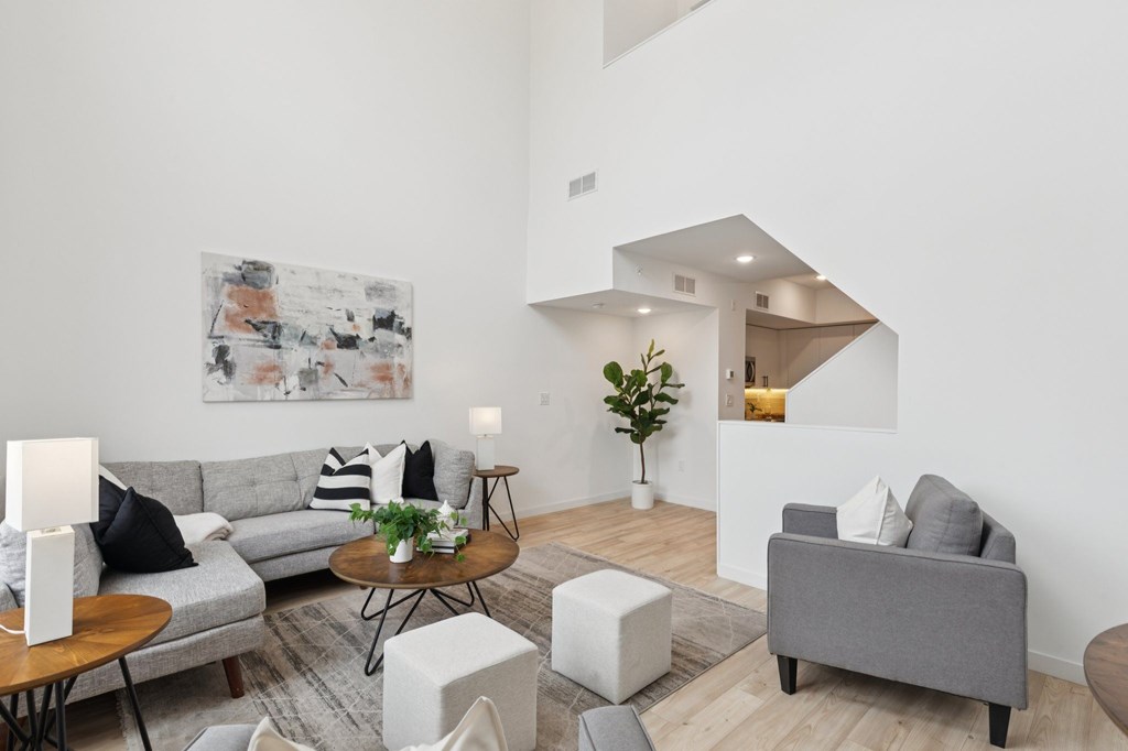 A living room with a grey couch, a coffee table, and a painting on the wall.