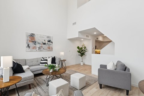 A living room with a grey couch, a coffee table, and a painting on the wall.