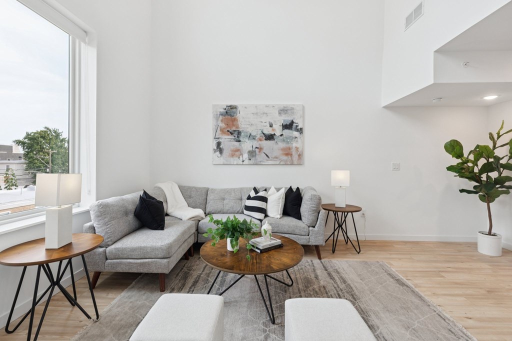 A living room with a grey couch, a coffee table, and a painting on the wall.