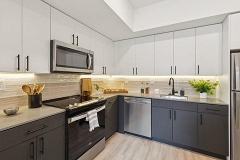 A modern kitchen with black cabinets and a white microwave above the stove.