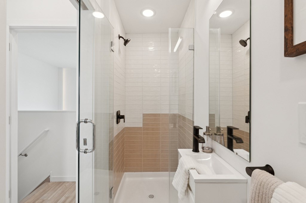 A bathroom with a white sink and a glass shower stall.