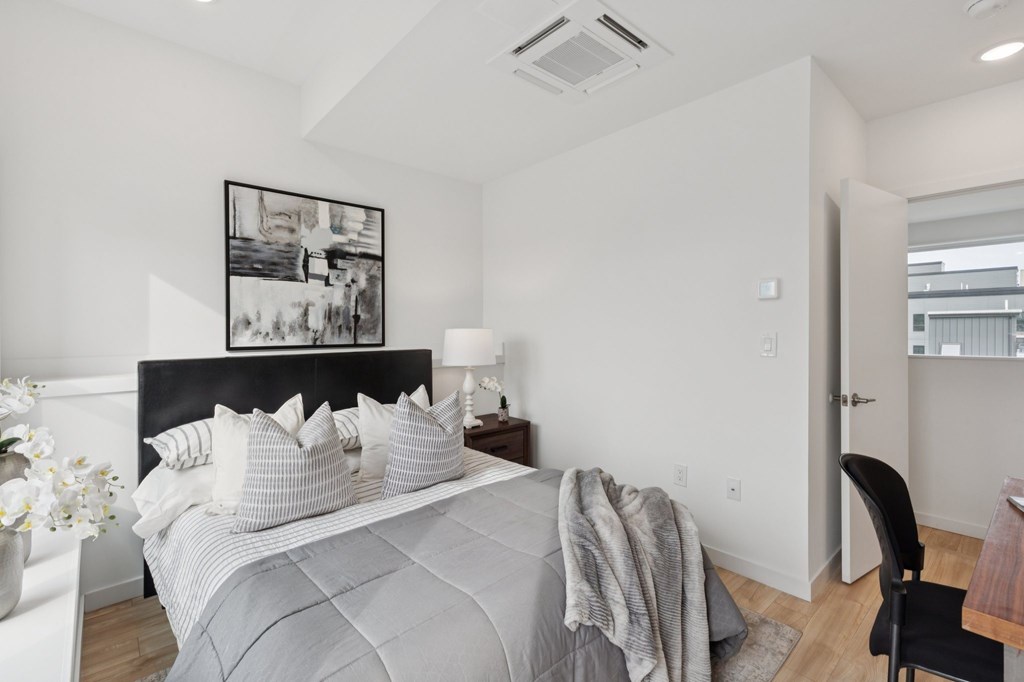 A bedroom with a bed, chair, and a picture on the wall.