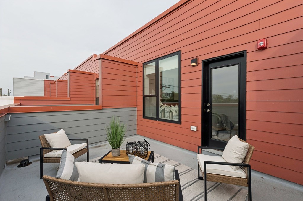 A patio with a table and chairs is on a red building.