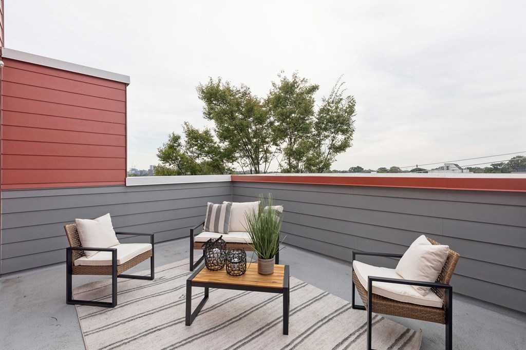 A patio with a table and chairs and a tree in the background.