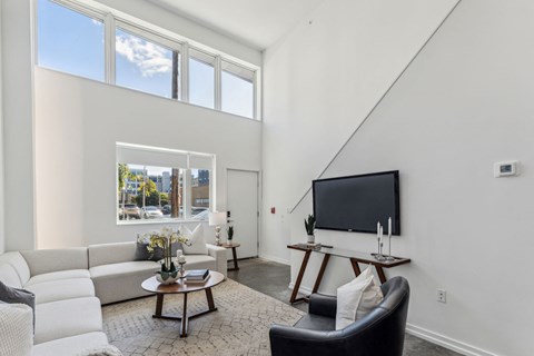 A living room with a white couch, a coffee table, and a flat screen TV.
