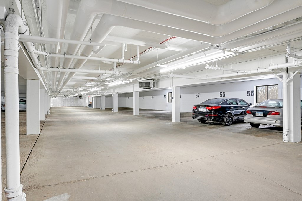 A parking garage with a few cars and numbered parking spots.