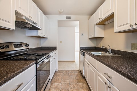 a kitchen with white cabinets and granite counter tops and a stove and sink