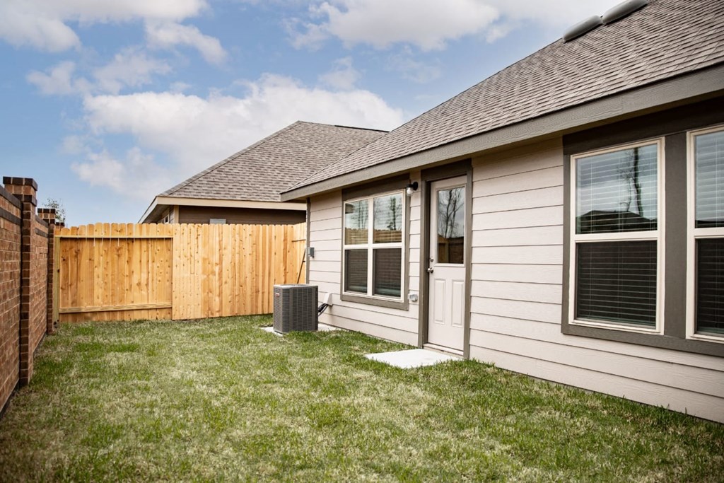 a home with a wood fence and grassy yard