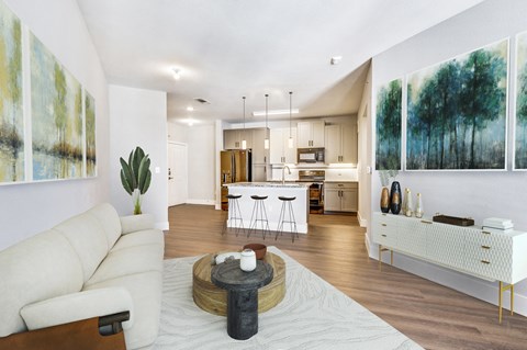 a living room with a couch and a table in front of a kitchen