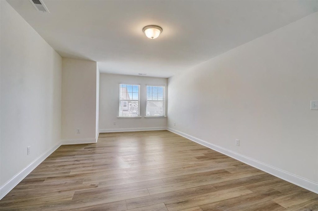 a bedroom with hardwood floors and a large window