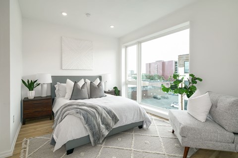 A bedroom with a large bed and a grey couch.