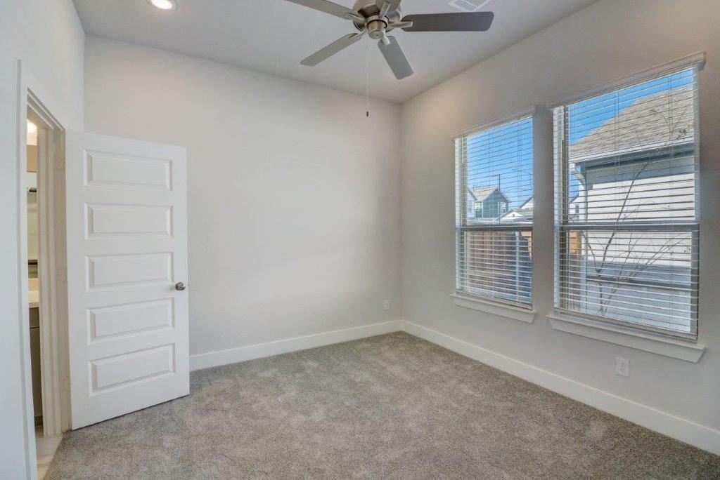 an empty bedroom with a ceiling fan and two windows