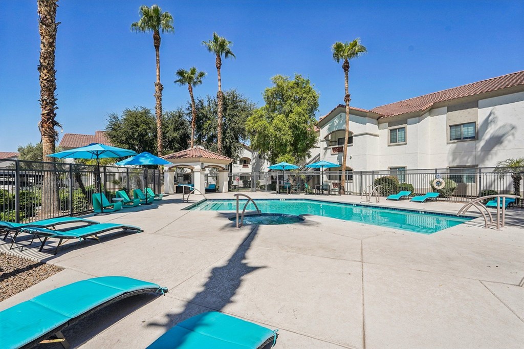 A pool surrounded by palm trees and sun loungers.