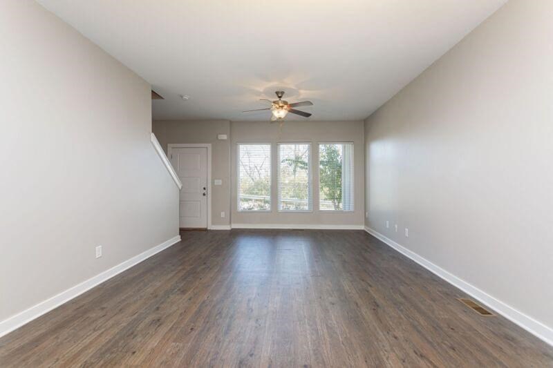 an empty living room with white walls and a ceiling fan