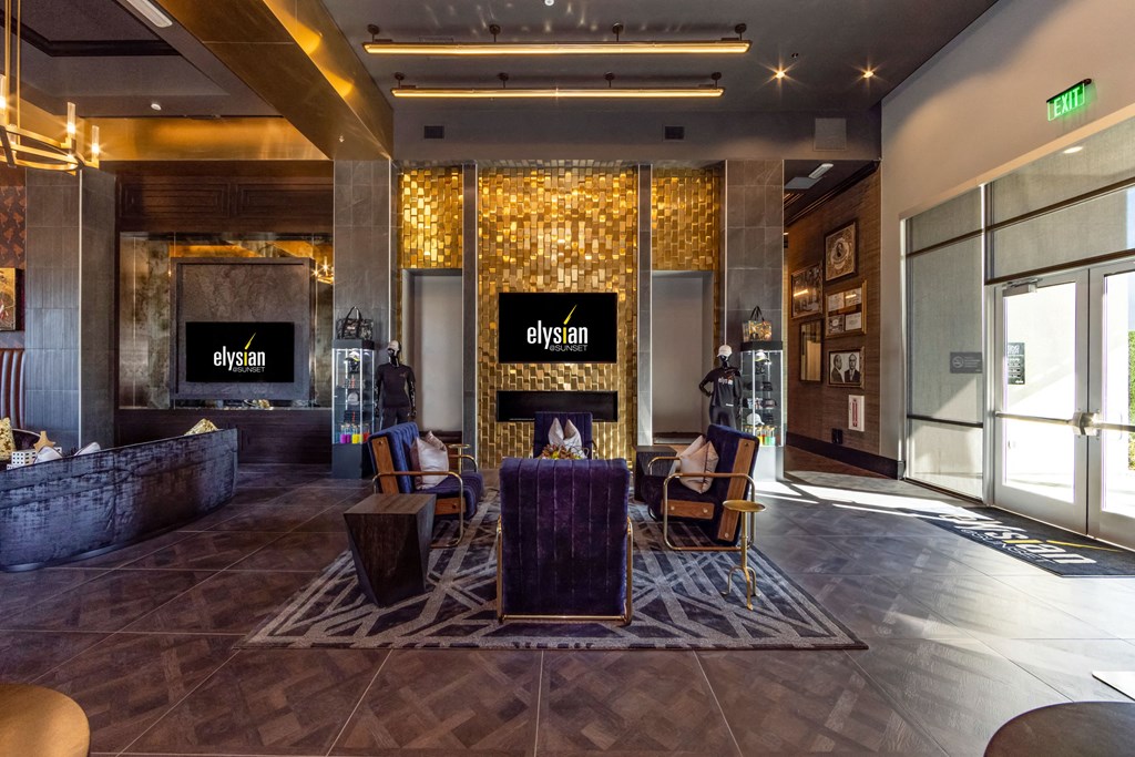 a lobby of a hotel with a fireplace and a table with chairs