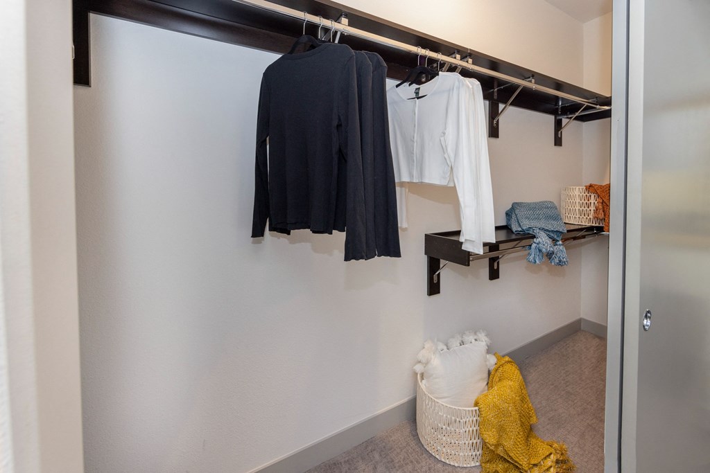 a walk in closet with a rack of clothes and a basket of laundry in it