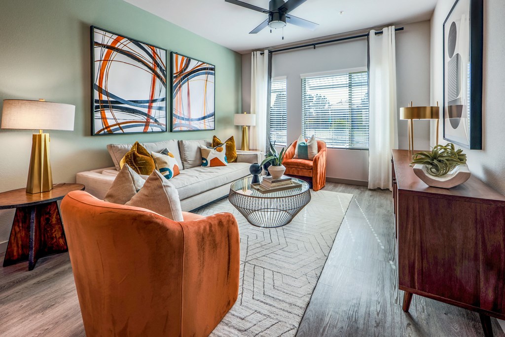 a living room with a couch and chairs and a ceiling fan