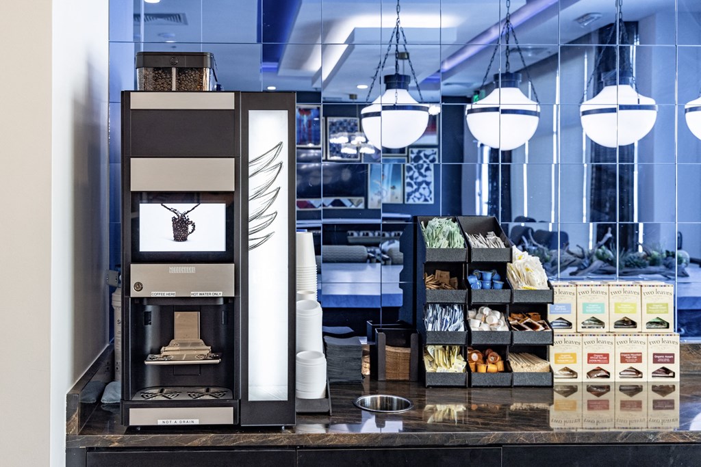 a coffee shop with a coffee machine and a display of coffee and cookies