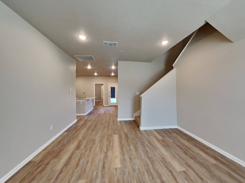 a renovated living room and kitchen with hardwood floors and white walls