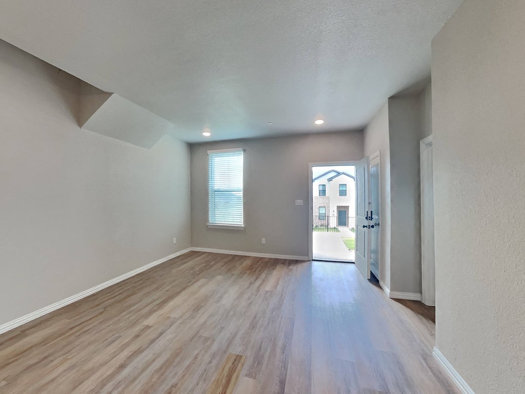 the living room and dining room of an empty house with wood flooring