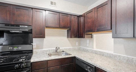 A kitchen with dark wood cabinets and a black stove.
