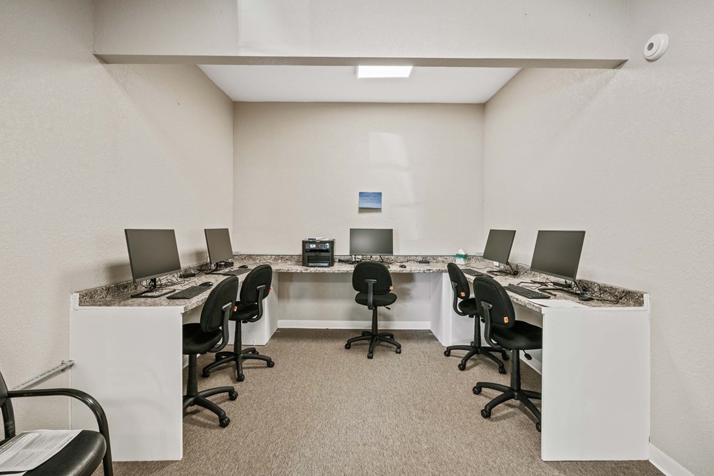 a conference room with long tables and chairs and a counter with computers