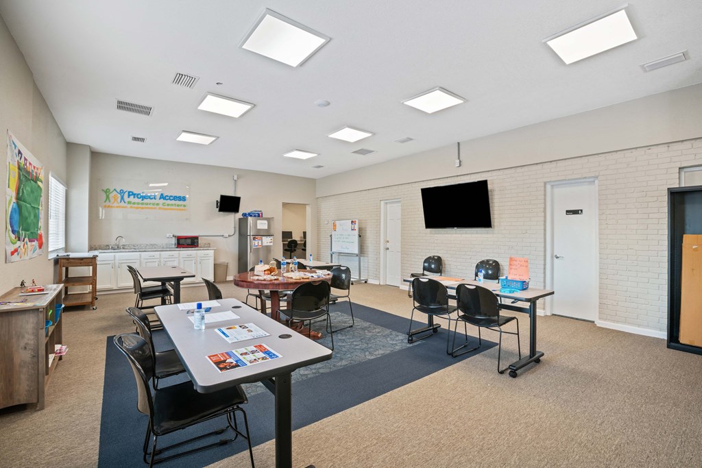 a classroom with tables and chairs and a tv on the wall