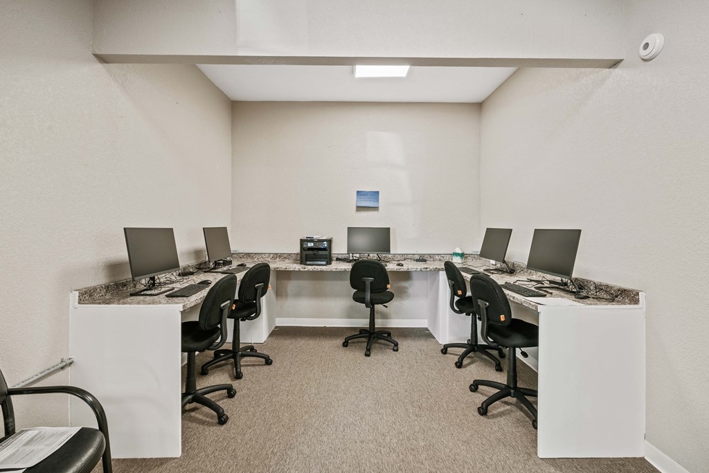 a conference room with long tables and chairs and a counter with computers