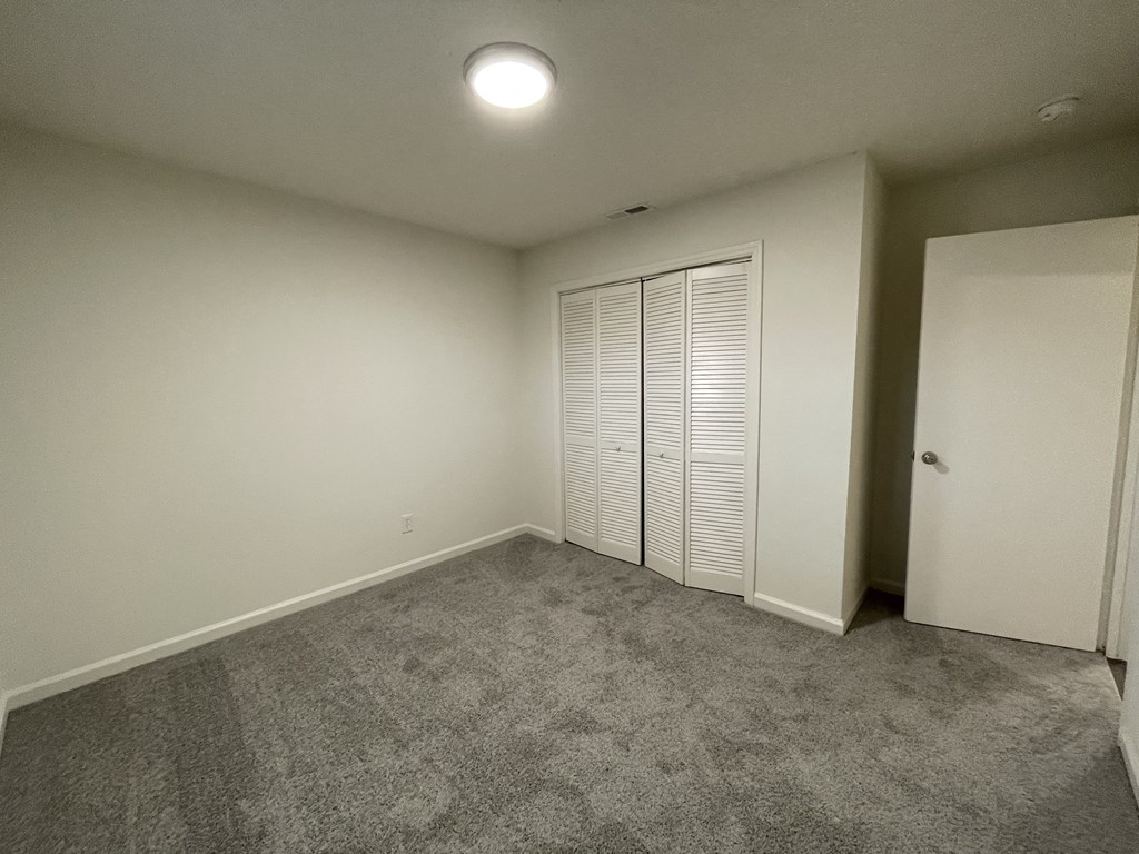 a room with carpet and white walls and a closet