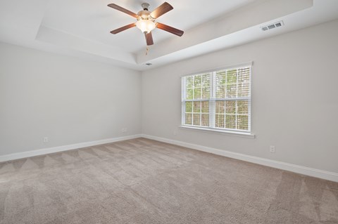 Harris Trail Luxury Townhomes for rent Richmond Hill, GA photo of an empty living room with a ceiling fan and a window