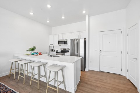 Open-concept apartment kitchen with spacious island, white cabinetry and stainless steel appliances