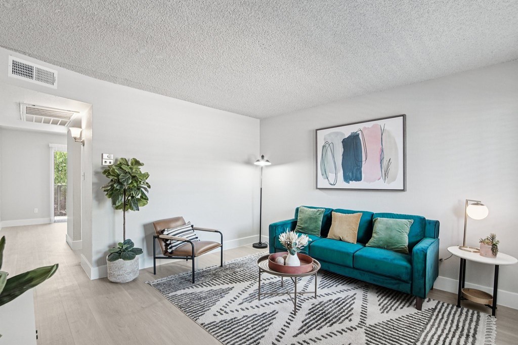 A living room with a blue couch and a painting on the wall.
