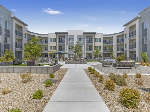 A concrete walkway leads through a courtyard surrounded by apartment buildings.
