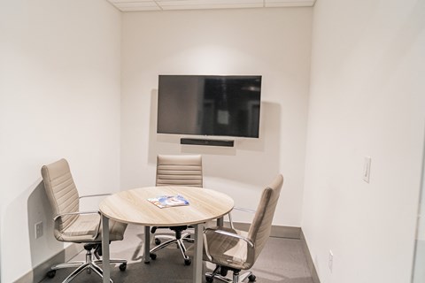 a conference room with a table and chairs and a television on the wall